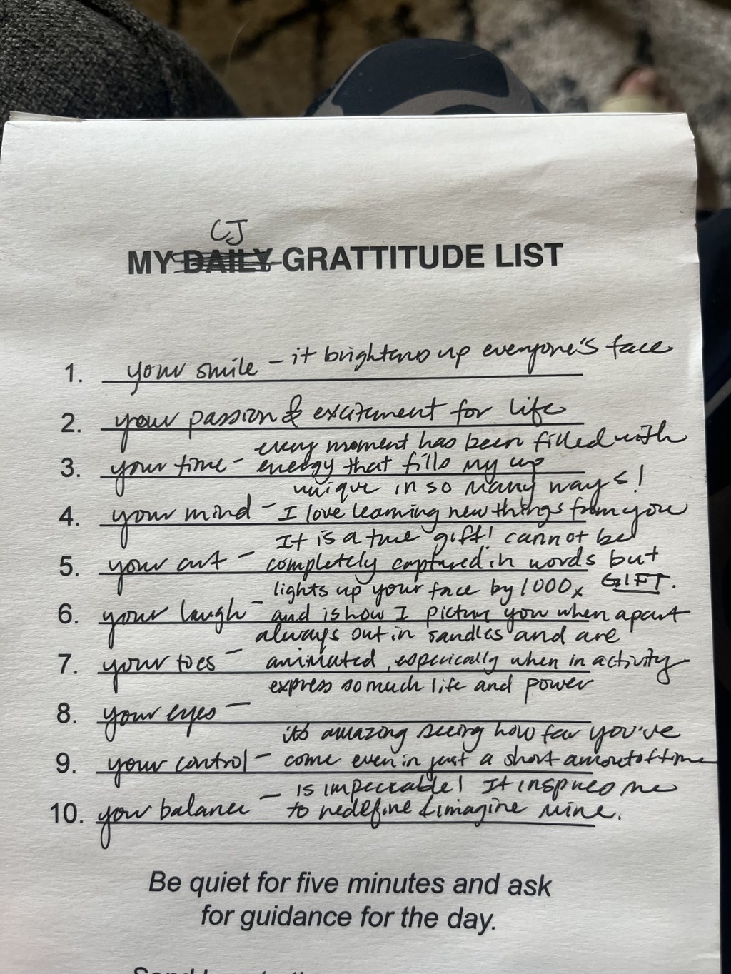 A handwritten piece of paper is displayed with a list titled 'MY DAILY GRATITUDE LIST.' The list contains ten items, each expressing gratitude for various attributes of someone named CJ, including smile, passion, time, mind, art, laugh, toes, eyes, control, and balance. The handwriting is neat and legible, with each item beginning with 'your' followed by the attribute being appreciated. The list also includes personal annotations about why these attributes are valued. At the bottom of the page, there is an instruction for a quiet reflection practice.