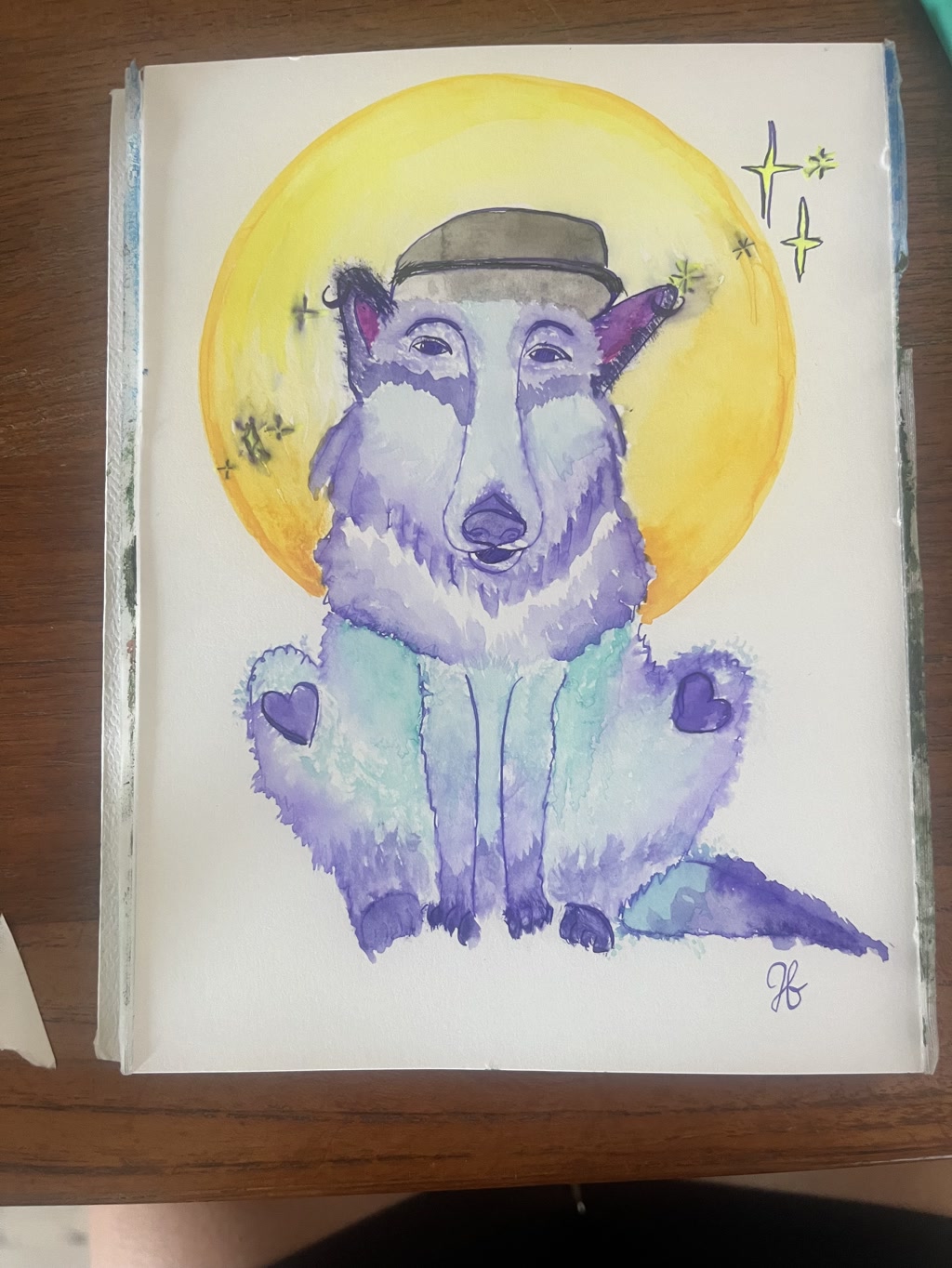 A watercolor painting depicts a wolf sitting down with its front paws visible and back legs stretched out. The wolf is wearing a brimmed hat and has a peaceful expression. The color palette of the wolf's fur includes shades of purple and blue, with distinct heart-shaped scars decorating its back legs. Behind the wolf, there is a yellow full moon adorned with small green stars, symbolizing a night sky.